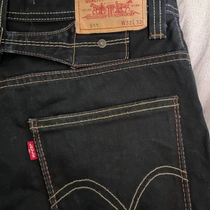 Levi's 511 svarta jeans W32 L32 - Säljer ett par svarta Levi's 511 jeans i storlek W32 L32. Klassisk femficksmodell med orange kontrastsömmar och Levi's röda logga på bakfickan. Jeansen har normal passform och är tillverkade i slitstarkt denimtyg.