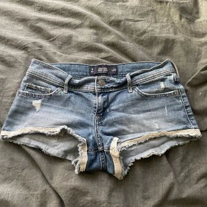 Blå jeansshorts med fransar från Hollister - Säljer ett par blå jeansshorts från Hollister med låg midja och slitna detaljer. PRIS GÅR ATT DISKUTERA. Skriv om ni har funderingar eller vill ha fler bilder🥰