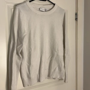 Vit stickad tröja från VILA - Säljer en enkel och stilren vit stickad tröja från VILA. Tröjan har rund halsringning, långa ärmar och ribbade muddar vid ärmslut och nederkant. 