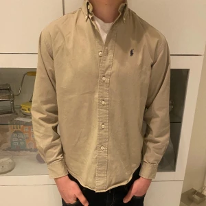 Polo ralph lauren skjorta  - Skjorta från Polo ralph lauren i storlek M sitter som en S. Skick 9,5/10 använd fåtal gånger. En beige skjorta som passar fint t sommarn. . Nypris: 1000kr. Mitt pris: 299kr. Modellen på bilden är 173 och brukar bära S. 