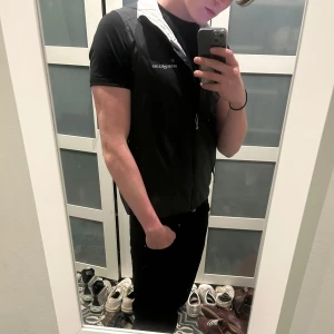 Svart väst från Henri Lloyd med dragkedja - Snygg svart väst från Henri Lloyd med grå insida och hel dragkedja framtill. Västen har två fickor med dragkedja och en sportig look, perfekt för lager-på-lager. Märkeslogga på bröstet.