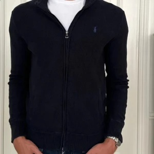 Ralph Lauren full zip - Säljer en mörkblå stickad kofta från Ralph Lauren. Storleken är M och skicket är bra