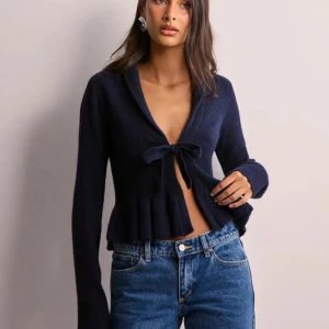 Mörkblå stickad kofta med knyt - Säljer en mörkblå stickad kofta med volangkant och knyt framtill. Perfekt att styla med jeans eller kjol. 💕