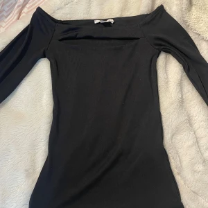 Svart långärmad tröja från Amisu - Säljer en svart, tight långärmad klänning från Amisu. Toppen har en enkel och stilren design med rak halsringning (litet ”hål” som design” och smal passform. Perfekt för dig som gillar minimalistisk stil. Helt oanvänd !! 