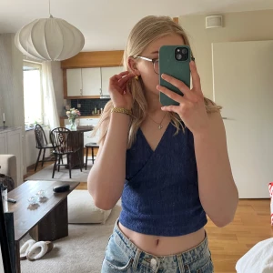 Blå omlottopp från Bik Bok - Säljer en blå omlottopp från Bik Bok i storlek S. Toppen är croppad och har en omlottdesign med breda axelband. Perfekt för varma dagar och enkel att matcha med jeans eller kjol.