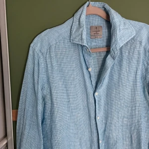 Ljusblå linneskjorta från La Chemise - Säljer en ljusblå långärmad skjorta från La Chemise Norrmalm i slim fit. Storlek 38 passar större S