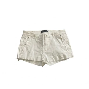 Of white shorts - Snygga beige shorts med normal passform och praktiska sidfickor. Perfekta för varma sommardagar och enkla att matcha med olika toppar. Stängs med knapp och dragkedja framtill. Inga fickor på baksidan.