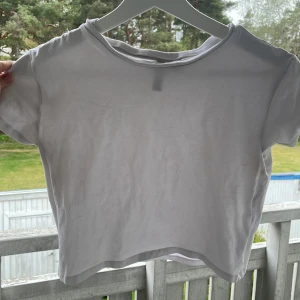 Vit croppad t-shirt från H&M Divided - En enkel och stilren vit croppad t-shirt från H&M Divided. T-shirten har korta ärmar och rund halsringning, perfekt för en avslappnad och trendig look. Tillverkad i mjuk bomull för extra komfort.