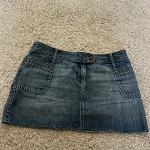 Jeanskjol med fickor - Säljer en super fin lågmidjad kort jeanskjol med  fickor fram och bak, den är perfekt till sommaren.I storlek S, i mycket bra skick.