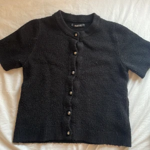 Svart kortärmad kofta från Gina Tricot - Svart kofta från Gina Tricot med korta ärmar och knappar framtill. Säljer pågrund av att de är för stor för mig. Ny pris 350.