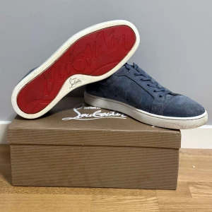 Blå mocka sneakers från Christian Louboutin - Snygga blå sneakers i mocka från Christian Louboutin med klassisk röd sula och vita kanter. Skorna är i bra skick om ni har några frågor är de bara att ställa‼️ Priset är också diskuterbart‼️☀️