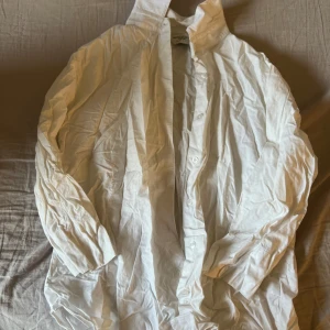 Vit skjorta från Russell Collection - Klassisk vit skjorta från Russell Collection med lång ärm och knappar framtill. Perfekt för en stilren look och enkel att matcha med olika outfits. Skjortan har en rak passform och är tillverkad i bomull. Storlek L