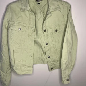 Ljusgrön jeansjacka från H&M - Snygg ljusgrön jeansjacka från H&M med silverfärgade knappar framtill. Jackan har två  med lock och knapp samt långa ärmar med knapp vid ärmslut. Perfekt för vår och sommar!
