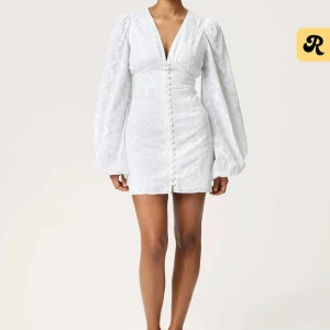 Adoore Florence dress vit - Superfin vit kortklänning från Adoore med broderade blommor, v-ringning och långa puffärmar. Klänningen har knappar framtill och markerad midja. Perfekt för sommarens alla tillfällen! Klänningen heter Florence dress. Är i storlek 32. Finns en liten fläck på insidan av klänningen men syns inte när den är på. Endast använd 1 gång innan. 