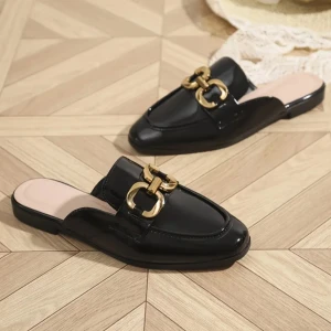 Svarta loafers med gulddetalj - Stilrena svarta loafers i syntetmaterial med snygg guldfärgad metallspänne framtill. Skorna har platt sula och öppen häl, vilket ger en modern look. Perfekta för dig som vill ha något klassiskt men ändå trendigt.