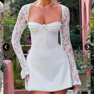 Vit spetsklänning med långa ärmar - Superfin vit klänning med långa spetsärmar och snörning i ryggen. Oandvänd och perfekt för sommaren eller studenten. Säljer pga hittat en annan klänning till studenten.