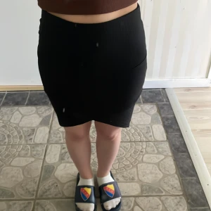 Svart ribbad kjol - Säljer en svart tight kjol från Gina Tricot med ribbad struktur i storlek S. Kjolen går lite över knäna och ganska stretchig
