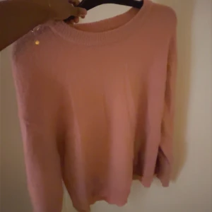 Rosa stickad tröja med rund hals - Mysig rosa stickad tröja med rundad hals och långa ärmar. Tröjan har en enkel och clean look utan mönster eller detaljer, perfekt för dig som gillar en chill och soft stil. Passformen är normal och materialet känns mjukt mot huden.