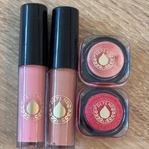 Depend läppglans - Två läppglans från Depend i rosa och nude med glansig finish, samt två läppglans i skimrande ljusrosa och intensivt rödrosa. Alla produkter har snygga svarta lock och Depend-logga i guld. Perfekt för dig som gillar färg och glans på läppar och ögon.