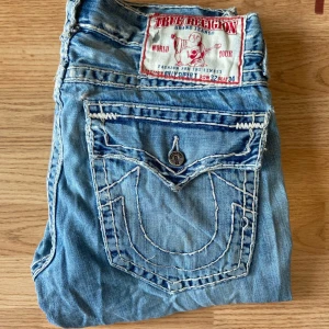 True Religion Jeans Billy Super T - True religion jeans, bootcut/baggy, storlek 32 med slitningar, knapparna där bak är dock utbytna, midja 43, längd 95, innerben 70, ben öppning 24cm. 