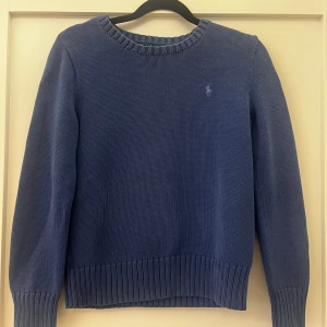 Blå stickad tröja från Polo Ralph Lauren - Snygg marinblå stickad tröja från Polo Ralph Lauren i 100% bomull. Barnstorlek M💙Super till hösten!