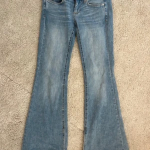 Bootcut jeans från ONLY ljusblå - Säljer ett par ljusblå utsvängda och lågmidjade jeans från ONLY de har en slits på insidan längst ner som ger en super snygg detalj, storlek S och längd 30