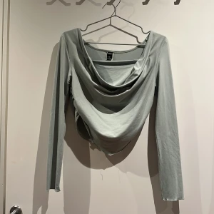 Omlottopp - Snygg ljusgrön omlottopp från SHEIN med draperad front och lång ärm. Toppen har en croppad passform med spetsig nederkant och är tillverkad i mjuk polyester.