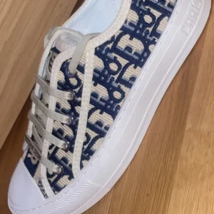  Dior sneakers💖 - Snygga sneakers från Dior med blått och beige monogrammönster, vit platt sula och snörning. Skon har tydliga Dior-loggor på både sula och snören. Ovandelen är i textil med broderade detaljer och sidorna har kontrasterande färger som ger en lyxig vibe.