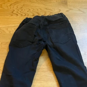 Svarta jeans med stretch och fickor - Snygga svarta jeans med klassisk femficksdesign och stretchig midja för extra komfort. Byxorna har raka ben och en knappstängning framtill. Perfekta för dig som gillar en enkel och stilren look med bra passform.