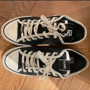 Svarta sneakers från Karl Lagerfeld - Snygga svarta sneakers från Karl Lagerfeld med vit sula och vita snören. Skorna är i textil med detaljer i syntet och passar därför perfekt till hösten 