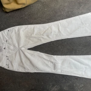 Vita Miss Me jeans med paljettdetaljer - Snygga vita jeans från Miss Me i storlek 29. Modellen har raka ben och coola bakfickor med paljetter och dekorativa knappar. Jeansen har klassisk femficksdesign och är gjorda i mjukt bomullstyg med stretch. Perfekt för dig som gillar att sticka ut med detaljer! Som nya !!!