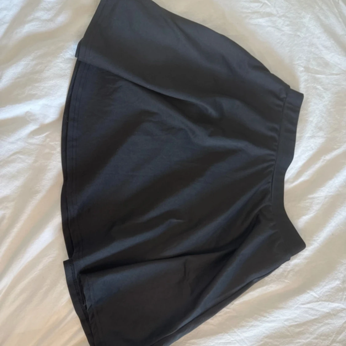 Svart kortkjol med utsvängd form