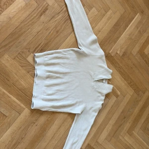 Zip hoodie  - Säljer en stilren ljusbeige  med ribbad struktur och lång ärm. Och är perfekt för lager-på-lager. Mjuk och skön känsla, passar dig som gillar minimalistisk stil. Med barn storlek 146-152