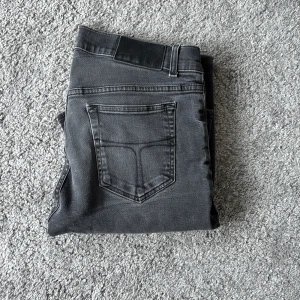 Grå jeans från Tiger of Sweden 32/34 - Snygga grå jeans från Tiger of Sweden i storlek 32/34. Modellen har klassisk femficksdesign, raka ben och normal passform. Jeansen är tillverkade i mjuk denim och har en stilren look som funkar till många olika outfits.