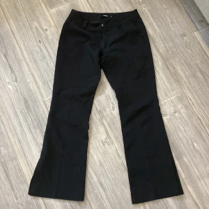 Svarta kostymbyxor med slits från BikBok - Svarta bootcut-byxor från BikBok i storlek 34. Snygg  modell med låg midja. Modellen är även i petit så de passar de som är korta! Passar mig som är 152 cm