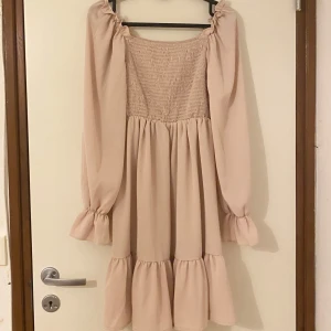 Ljusbeige volangklänning med puffärm - Supersöt ljusbeige klänning med volanger och puffiga långärmar.