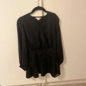 Svart glittrig kortklänning Gina Tricot - ALDRIG ANVÄNT 💕Supersnygg svart kortklänning från Gina Tricot med glittriga detaljer. Klänningen har omlott-look, markerad midja och volang nedtill. 