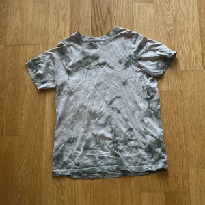 Tie-dye t-shirt från Jack & Jones - Snygg t-shirt från Jack & Jones med coolt tie-dye mönster i grått och vitt. Tryckt logga på bröstet och klassisk rund hals. Perfekt för dig som gillar streetstyle och vill ha en chill vibe. Materialet är mjuk bomull och modellen är normal passform med korta ärmar.