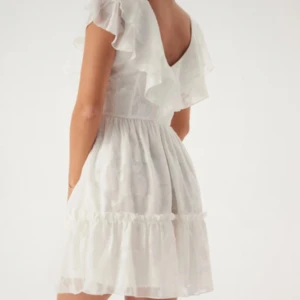 Vit kortklänning med volanger / studentklänning - Supersöt vit kortklänning med volanger på axlarna och v-ringad rygg. Perfekt studentklänning. Prislapp kvar💕