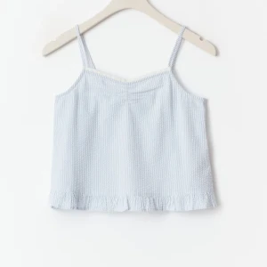 2 stycken (Ljusblå och ljusrosa) linnetoppar med volang - Gina Tricot - Y cotton Singlet  - 2 stycken Korta linnen i  bomull med en v-ringning. Linnet är blått och vitt och har generös passform. Det har en liten rynkad söm fram, en spetskant fram, en nedervolang och mjuk seersucker-kvalitet. Helt nya och oanvända. 🩷storlek 170 (sitter som en S) 