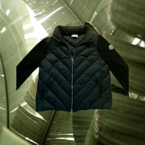Svart cardigan från Moncler - Svart pufferjacka från Moncler med snyggt quiltat mönster och dragkedja framtill. Jackan har långärmade svarta ärmar med Moncler-logga på vänster arm. Materialet är polyester och dun, perfekt för kyliga dagar. Modern och stilren look. Funkar till både tjejer och killar den är storlek xs men passar kan nog passa s också vet tyvärr ej ifall den är äkta. Hör av er vid någon fråga! Pris ej hugget i sten vid snabb affär!