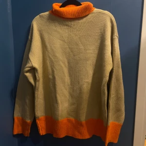 Höstig stickad tröja - Höstig beige stickad tröja med orange krage. Storleken står inte men bedömmer att den är S-M. Köpte second hand men ser hemmagjord ut