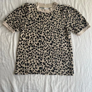 Kortärmad tröja i leopardmönster - Kortärmad leopardmönstrad tröja i viskos o elastan med puffärmar från Lindex. Endast använd ett fåtal gånger o i ny skick samt hel o ren. Storlek 146/152 (Nypris kr)