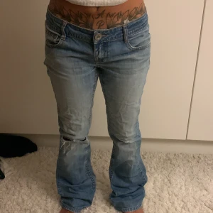 Ljusblå bootcut jeans med låg midja - Säljer ett par ljusblå jeans med bootcut passform och låg midja. Från only . Klassisk femficksdesign, slitningar vid knäet och snygga detaljer på bakfickorna. Jeansen har en avslappnad vibe och är tillverkade i mjukt denimtyg. Perfekta för dig som gillar retrostil och bekväma jeans. Midjemått: 38cm
