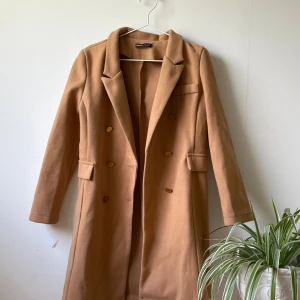 Kappa - Snygg figursydd kamelfärgad kappa. Perfekt till hösten i mycket bra skick. Knapparna har lite repor men inget som märks tydligt. Skriv vid intresse eller tryck köp nu👌