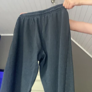 Mörkgrå mjukisbyxor med resår - Säljer ett par mörkgrå mjukisbyxor med elastisk midja och muddar vid bensluten. Byxorna har en loose passform och är gjorda i mjukt bomullsmaterial, perfekta för chill dagar hemma eller när du vill vara extra bekväm.
