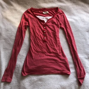 Röd långärmad tröja Hollister  - Röd långärmad tröja från Hollister. Vit spets ingår ej. Tröjan har ett pyttelitet hål i ryggen (sista bilden) som knappt syns! 