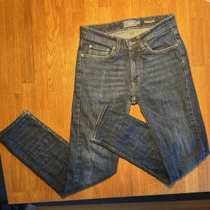 Blåa jeans från Dressmann, regular fit - Tjena! Idag säljer jag ett par blå jeans från Dressmann i regular fit med en klassisk ficksdesign och  ”kopparfärgade” sömmar. Jeansen har dragkedja i gylfen och raka ben. Materialet är slitstarkt och jeansen ska köpas av dig som vill se stilig ut men samtidigt lite ”chill”. Hoppas du blir nöjd🙂!