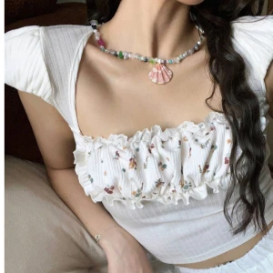 Milkmaid Vit blommig blus med puffärmar - Supersöt vit blus med blommigt mönster på bröstet och puffiga korta ärmar ifrån Remolatcha.  Toppen har ribbad struktur, volangdetaljer och en snygg knytning i ryggen som ger en öppen rygg-look. Jätte fin kvalité på material. Det är en limited edition topp!! Helt ny och oanvänd. 🩷