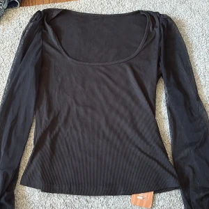 Svart ribbad topp från Shein - Säljer en stilren svart ribbad topp från Shein med transparenta långa ärmar. Toppen har en rundad halsringning. Passar bra till det mesta. Aldrig använd och därmed lappen kvar.